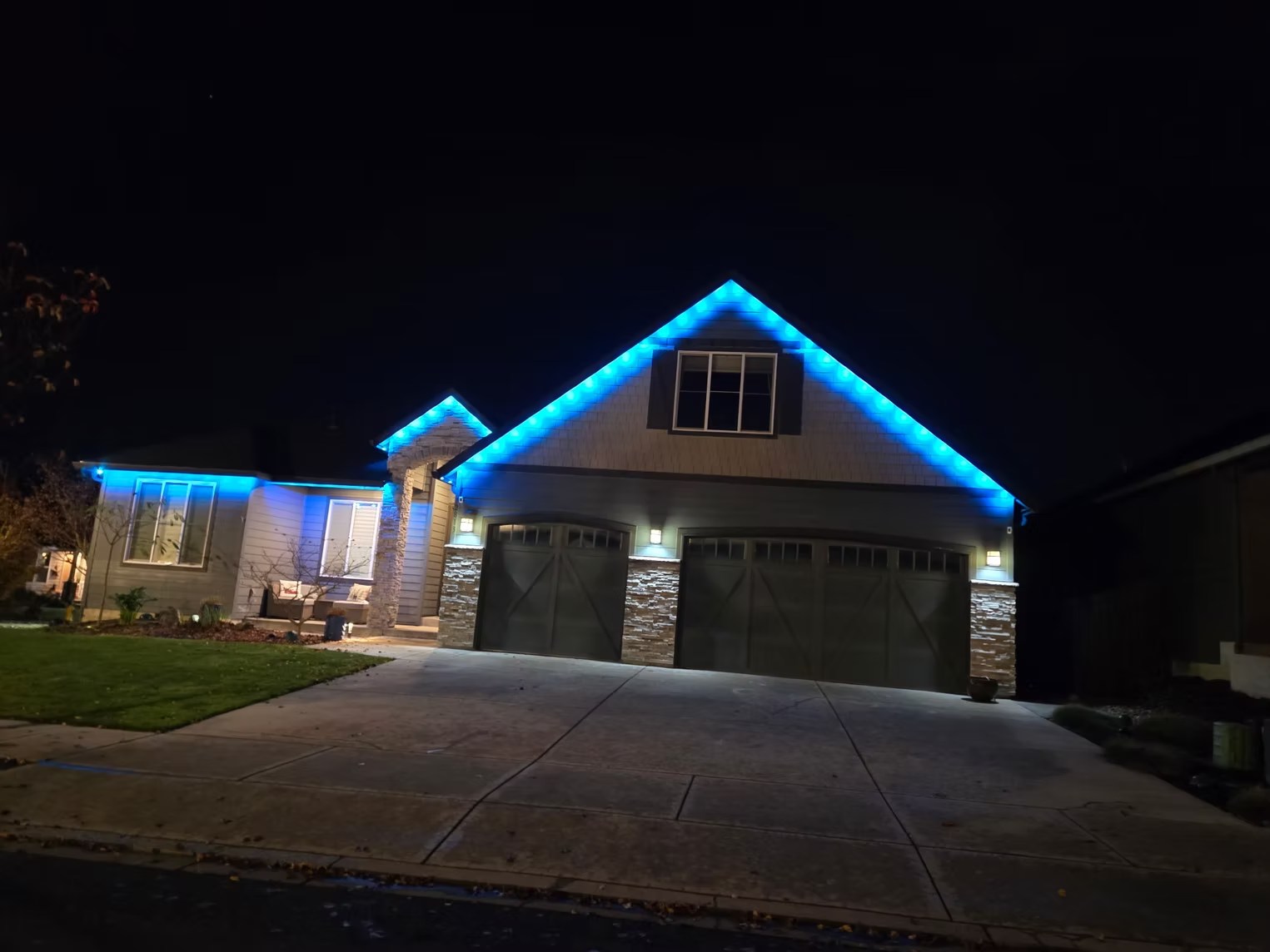 Blue roofline lighting above a three-car garage at night
