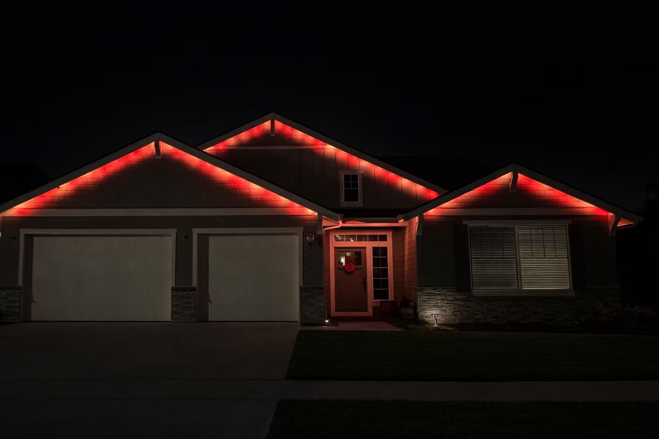 Red lighting following the peaks and eaves of a single-story home at night