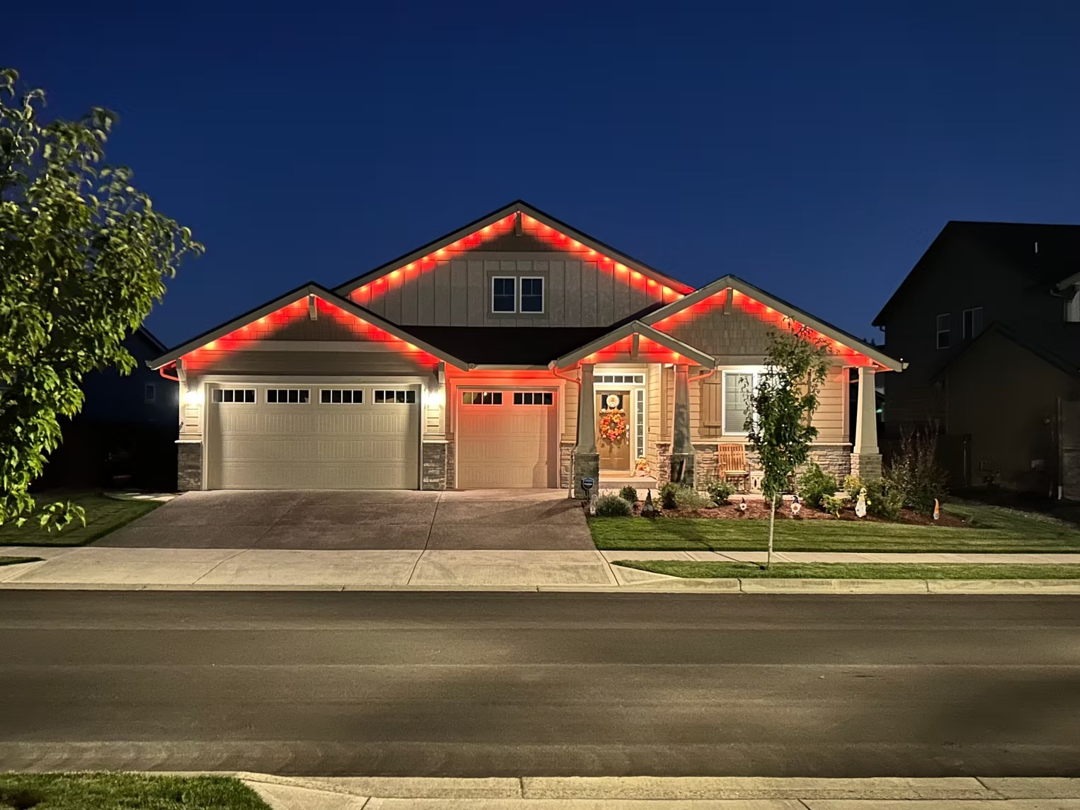 Red and warm-white lights following a home's roof peaks and eaves at dusk